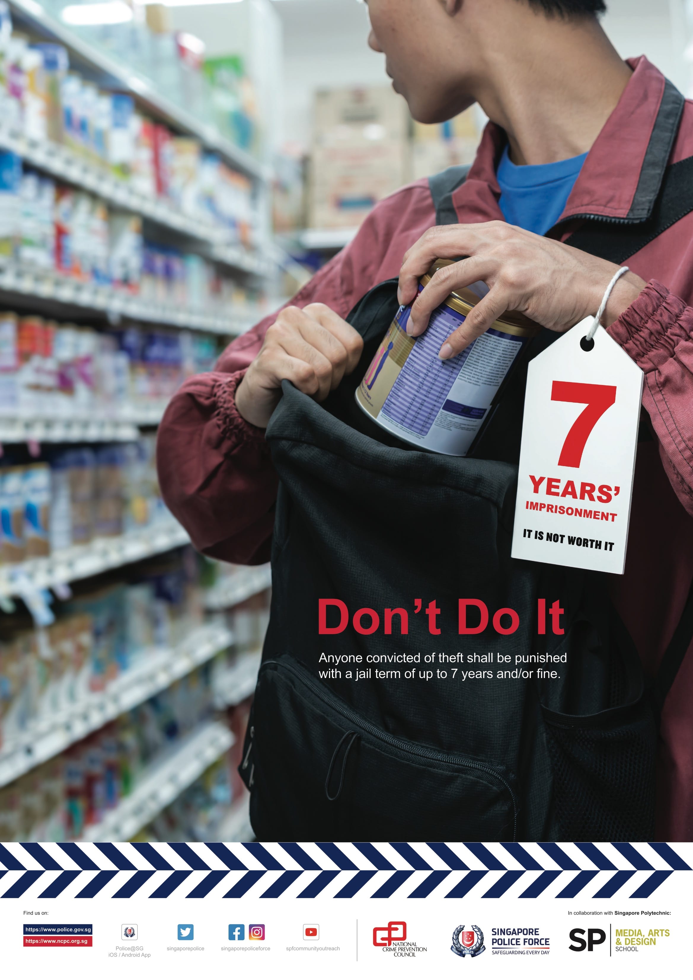 A close-up framing shows a person wearing a pinkish-red jacket slipping a cylindrical item—such as a tin or container—into a black backpack in a supermarket aisle, while a hanging price-tag style notice reads "7 YEARS' IMPRISONMENT IT IS NOT WORTH IT".